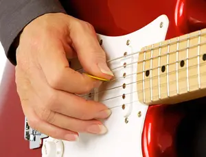 Guitarist using hybrid picking with a flatpick and fingers on electric guitar