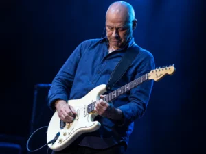 Experienced guitarist playing a white electric guitar on stage – choosing the right type of guitar